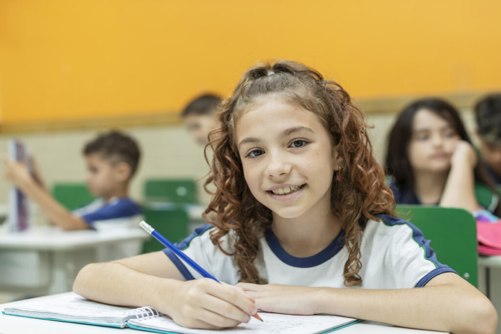 Aluna em sala de aula durante atividade pedagógica, em contexto de certificação IB e educação internacional